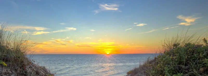 Sunset over the water between two dunes