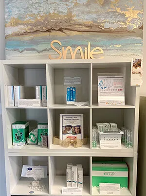 A shelf of dental care products beneath a gold “Smile” sign