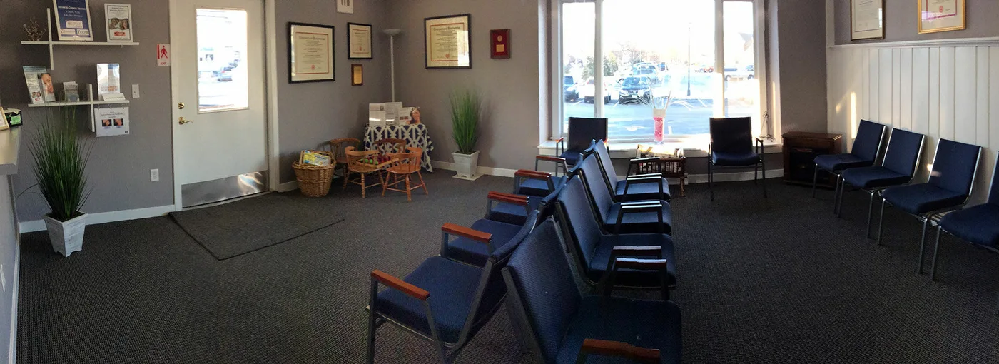 The Falmouth Family Dentistry waiting room, with blue chairs and a sunny window