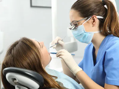 A hygienist cleaning a patient&rsquo;s teeth