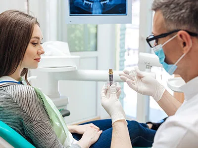 A dentist showing a patient a dental implant